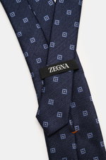 Zegna Seidenkrawatte navy/rauchblau gemustert, Nahaufnahme von oben, reine Seide, dezenter Glanz, grafisches Webmuster, kontrastfarbener Futterstoff, Made in Italy, Breite ca. 8 cm.