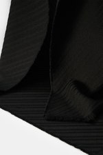 Close-up front-angle view of the Emporio Armani Scarf black showing pure virgin wool with a soft, textured feel, distinctive striped weave pattern, all-around fringed edge, dimensions approx. 180 cm x 38 cm.
