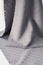 Emporio Armani Scarf grey shown from a close-up angled perspective, featuring pure virgin wool, soft textured feel, distinctive striped weave pattern, all-around fringed edge, dimensions approx. 180 cm x 38 cm.