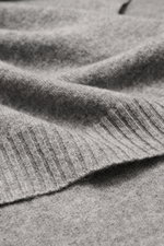 Nahaufnahme des cremefarbenen 04651/ A trip in a bag Cashmere Schals mit weichem Griff und Rippstrick-Kanten, perspektivisch von oben fotografiert.