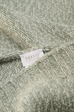 Nahaufnahme des 04651/ A trip in a bag Schal 'Mouline Scarf' salbei/hellgrau meliert mit weichem Woll-Cashmere-Mix und Rippenkante, liegend fotografiert.