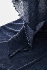 Nahaufnahme des Fedeli Cashmere Tuchs 'Yeti' graublau aus softem, voluminösem Griff mit geflammter Optik und offenen Saumkanten, fotografiert aus schräger Perspektive.