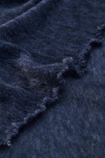 Nahaufnahme des Fedeli Cashmere Tuchs 'Yeti' graublau, weich und voluminös mit geflammter Optik und offenen Saumkanten, aus schräger Perspektive.