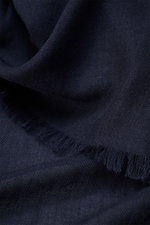Nahaufnahme des Colombo Cashmere-Seiden-Schals navy mit schmalem Fransensaum, rollierten Kanten, sehr weichem Griff, leichter Qualität, Maße ca. 192x70 cm, fotografiert aus schräger Perspektive. Mix aus Cashmere und Seide.