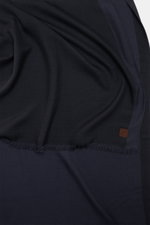 Nahaufnahme des Colombo Cashmere-Seiden-Schals dark navy von oben fotografiert, mit weich fallendem Stoff, schmalem Fransensaum und Logo-Patch.