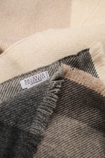 Nahaufnahme des beige/grau/anthrazit karierten Brunello Cucinelli Schals aus Wolle und Cashmere mit schmalem Fransensaum, von oben fotografiert.