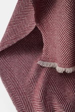 Close-up top-down view of Brunello Cucinelli Cashmere scarf grey/bordeaux patterned showing classic herringbone weave and fringe edge. 

<p>Quiet-luxury label BRUNELLO CUCINELLI is known for its elegant, timeless cashmere creations – like this two-tone wo