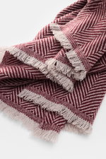 Close-up top view of Brunello Cucinelli Cashmere scarf grey/bordeaux patterned, showcasing classic herringbone weave and soft fringe.

<p>Quiet-luxury label BRUNELLO CUCINELLI is known for its elegant, timeless cashmere creations – like this two-tone wove