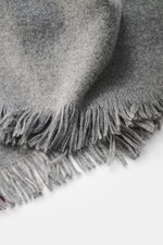 Close-up top-down view of the Brunello Cucinelli Cashmere scarf dark grey/bordeaux showing soft texture, narrow fringed edge, pure cashmere, very soft touch, dimensions approx. 162 cm x 44 cm.