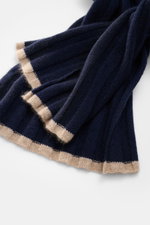 Close-up view of the Brunello Cucinelli Cashmere Scarf navy showing its classic ribbed knit design and fine soft texture with beige edges. Elegant through the winter with BRUNELLO CUCINELLI: This scarf made of pure cashmere in a distinctive ribbed knit de
