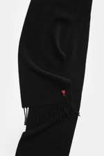 Ami Paris Schal schwarz aus reiner Wolle, seitlich fotografiert, mit beidseitiger Fransenkante und rotem 'Ami de Cœur'-Stitching, weich und unisex.