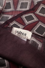 Close-up front view of the Altea Scarf dark violet/burgundy/dark grey patterned showing its smooth texture, graphic print, rolled edges, narrow fringed hem, made of a mix of wool and modal, lightweight quality, dimensions approx. 182 cm x 53 cm.
