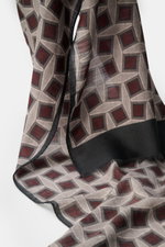 Altea Scarf anthracite/taupe/burgundy patterned shown from a close-up front angle, featuring a graphic print with a mix of wool and modal, smooth texture, lightweight quality, rolled edges, narrow fringed hem, dimensions approx. 182 cm x 53 cm.