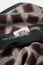Close-up shot from above of the Altea Scarf anthracite/taupe/burgundy patterned showing rolled edges, narrow fringed hem, graphic print, smooth texture, lightweight mix of wool and modal, dimensions approx. 182 cm x 53 cm.