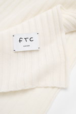 Close-up top-down view of FTC Cashmere scarf off white showing wide rib knit pattern and large woven logo label.

Description: 
<p>An elegant, sustainably produced accessory for cold days: This scarf with rib knit pattern by FTC is made of luxurious, pure
