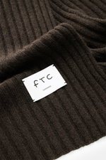 Alt tag (max 125 characters): Close-up top view of FTC Cashmere scarf dark brown with wide rib knit pattern and white woven logo label.

Additional description:  
<p>An elegant, sustainably produced accessory for cold days: This scarf with rib knit patter