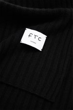 Close-up front view of FTC Cashmere scarf black showing wide rib knit pattern and large white woven label with logo on soft pure cashmere.

Description: 
<p>An elegant, sustainably produced accessory for cold days: This scarf with rib knit pattern by FTC 