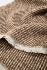 Close-up angled view of 04651/ A trip in a bag Scarf 'Fancy Twill' grey brown/cream showing coarse twill structure, narrow fringed edge, soft feel, made of virgin wool, baby alpaca, and high-quality microfiber, dimensions approx. 180 cm x 48 cm.