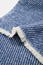 Close-up angled view of the 04651/ A trip in a bag Scarf 'Fancy Twill' dark blue/cream showing soft feel, coarse twill structure, narrow fringed edge, made of mix of virgin wool, baby alpaca, and high-quality microfiber, dimensions approx. 180 cm x 48 cm.
