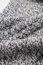 Close-up front view of the 04651/ A trip in a bag Scarf offwhite/navy melange showing coarse and cable knit patterns in a soft virgin wool and cashmere mix.