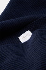 Nahaufnahme des navyfarbenen 04651/ A trip in a bag Cashmere Schal navy mit klassischem Patentstrickmuster und Label, feines Strickbild, reiner Cashmere, sehr weicher Griff.