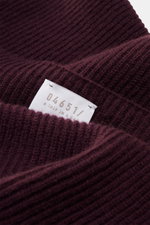 Nahaufnahme des dunkelvioletten 04651/ A trip in a bag Cashmere Schals aus reinem Cashmere im klassischen Patentstrick, Detailperspektive zeigt feines Strickbild und Etikett.