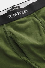 Nahaufnahme der sportlichen, monochromen Tom Ford Boxershorts grün aus elastischer Baumwolle mit seitlichem Eingriff, Slim Fit und schwarzem Bund mit weißem TOM FORD-Stitching.
