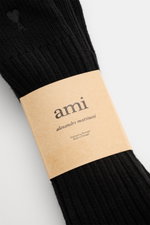 Close-up top view of Ami Paris Strümpfe 3er-Set schwarz, ribbed black socks with a beige label by Alexandre Mattiussi, made in Portugal.

Description: <p>Vom Basic zum Statement mit Herzensangelegenheit schaffen es die Strümpfe im 3er-Set von AMI PARIS, d
