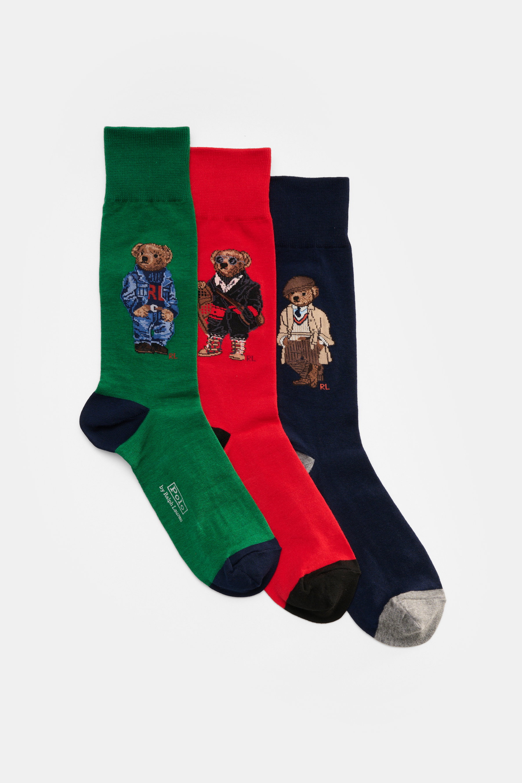 Polo Ralph Lauren Strümpfe 3er-Set grün/navy/rot shown from a top-down view, featuring three socks in green, red, and navy blue. Each sock displays a distinctive teddy bear print wearing stylish outfits. Stylish statements for the cold season: The socks w