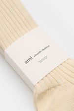 Close-up front angled view of Ami Paris Socks pack of 3 pairs cream, rib knit with wide bands and signature heart stitching.

<p>French label AMI PARIS has added its signature stitching to transform this pack of 3 pairs of socks from a basic to a passiona