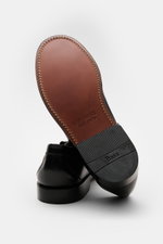 G. H. Bass Penny Loafer schwarz/weiß aus edlem Glattleder, von hinten mit sichtbarer lederner Sohle und kautschukverstärktem Absatz.