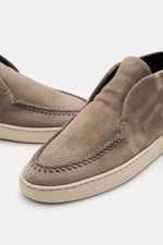 Officine Creative Loafer 'Herbie' taupe photographed from a front-side angle, showing soft suede, decorative stitching, slim silhouette, leather lining, rubber sole, and grosgrain loop for easy slip-on.