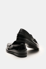 Church's Penny Loafer 'Rowley' schwarz aus poliertem Glattleder in schräger Nahaufnahme, zeigt Ziernähte, Penny-Strap, Ledersohle, Goodyear-welted.