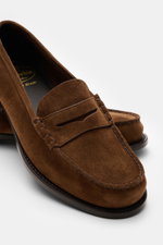 Church's Penny Loafer 'Rowley' braun aus geschmeidigem Veloursleder mit Ziernähten, Penny-Strap und lederner Laufsohle, seitlich schräg fotografiert.