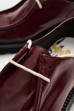 Close-up angled view of Collegium Derby 'Pillar Moc-Toe' bordeaux showing polished smooth leather, narrow silhouette, open two-eyelet lacing, cap toe stitching, leather lining, and rubber lug sole. Eyecatcher für die Übergangszeit: Der 'Pillar Moc-Toe' De