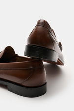 G.H.Bass Penny Loafer 'Weejuns Larson' braun aus edlem Glattleder, schmal zulaufend, mit Penny Strap und Zierschnürung, seitlich hinten fotografiert.