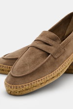 Nahaufnahme der Castañer Espadrilles 'Nacho T' taupe aus Veloursleder mit Penny-Strap, Jute-Umrandung und flexibler Kautschuksohle, seitlich frontal fotografiert.