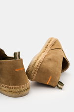 Castañer Espadrilles 'Joel' hellbraun shown from a rear-side angle, featuring soft velour leather, jute trim, side elastic inserts, pull tabs, decorative rear stitching, and flexible rubber sole, embodying a casual classic summer style. Legerer Klassiker: