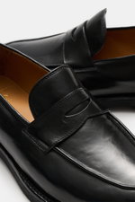 Close-up side perspective of Officine Creative Penny Loafer 'Opera Flexi' black in noble smooth leather with penny strap, toe cap, and Goodyear welt.