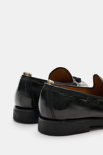 Rear close-up view of Officine Creative Tassel Loafer 'Opera Flexi' braun in polished leather with Goodyear welted sole and natural rubber outsole, featuring tassels, leather lining, and signature grosgrain pull loop, showcasing a modern take on classic o