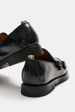 Close-up rear and side view of Officine Creative Double Monk 'Opera Flexi' black shoes showcasing noble smooth leather, double monk strap, slightly tapered silhouette, decorative toe cap stitch, grosgrain pull tab, leather lining, and natural rubber outso