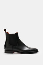 Santoni Chelsea Boot 'Adrian' black shown from side view, polished smooth leather, narrow tapered silhouette, side elastic inserts, pull tab, leather lining, leather sole with rubber insert, classic Italian style for suit or casual office look.