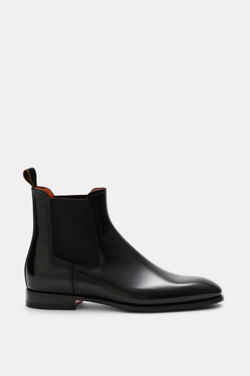 Santoni Chelsea Boot 'Adrian' black shown from side view, polished smooth leather, narrow tapered silhouette, side elastic inserts, pull tab, leather lining, leather sole with rubber insert, classic Italian style for suit or casual office look.