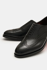 Santoni Oxford 'Collin' schwarz aus geschmeidigem Glattleder mit Full-Broguings, schmal zulaufend, Sechs-Loch-Schnürung, seitliche Nahaufnahme.