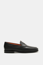 Santoni Loafer 'Carter' schwarz aus feinem, handgefärbtem Glattleder, seitlich fotografiert, mit orangener Innensohle und Ledersohle.
