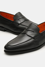 Santoni Loafer 'Carter' schwarz, frontal und seitlich fotografiert, feines Glattleder, Penny-Strap, handgefärbt, Steppnaht, orange Innenfutter.