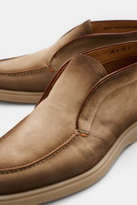 Nahaufnahme von zwei Santoni Desert Boot 'Detroit' taupe aus geschmeidigem Veloursleder mit schmal zulaufender Silhouette, kontrastfarbiger Ziernaht und flexibler Gummisohle, fotografiert leicht von oben.