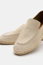 Close-up front-side view of Tom Ford Espadrilles beige made of soft velour leather with decorative front seam, leather lining, espadrille-style trim, and flexible rubber sole, ideal for summer vacations.