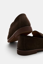 Henderson Penny Loafer 'Modica' dark brown shown from a low rear angle, made of supple suede leather with narrow tapered silhouette, typical penny strap, decorative stitch on front cap, Goodyear-welted, leather lining, natural rubber outsole, and practica