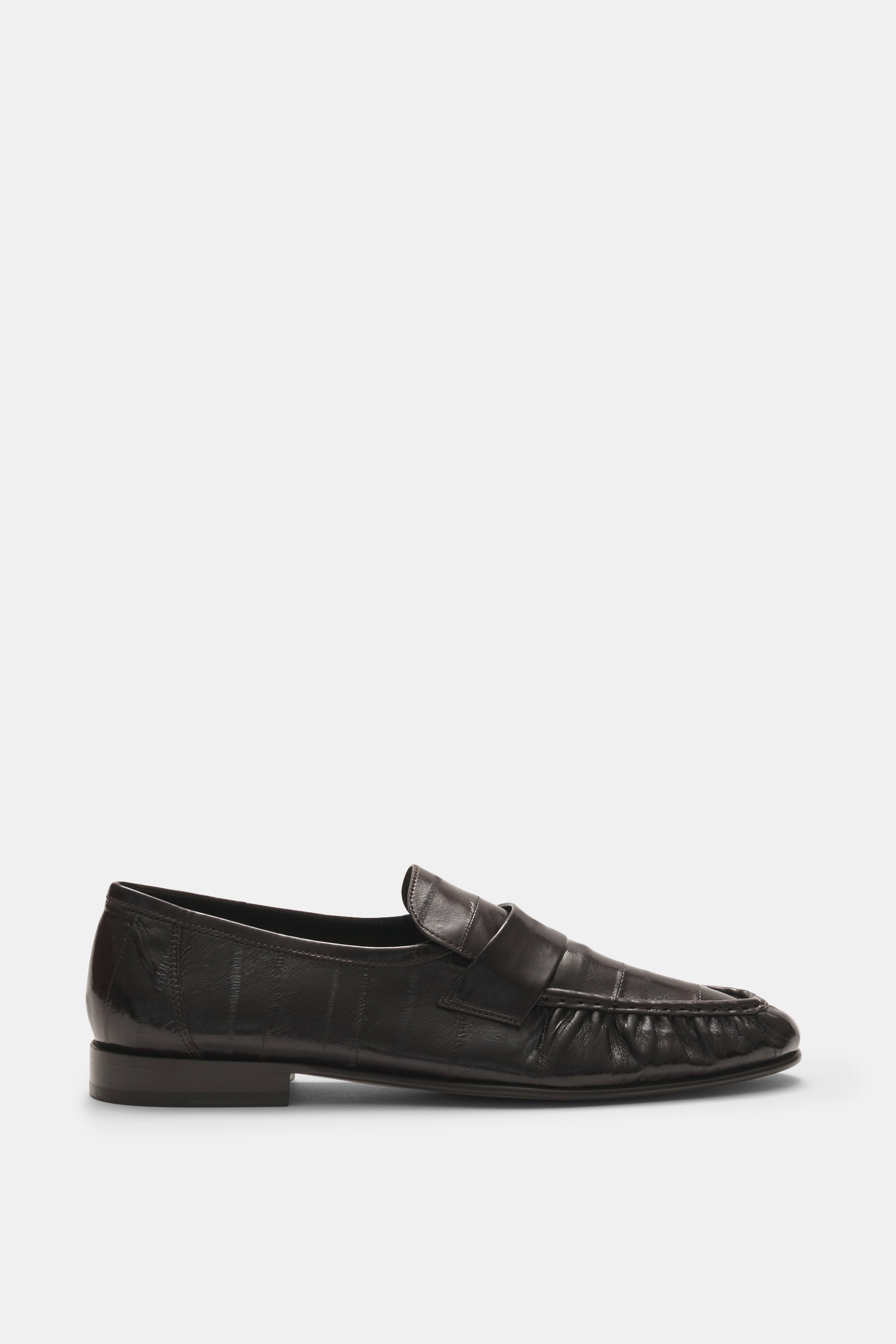 Side view of The Row Loafer dark brown in supple eel leather with a typical strap, narrow tapered silhouette, decorative toe seam, leather lining, and rubber sole inserts, hand-finished in Italy for an elegant and exotic look.